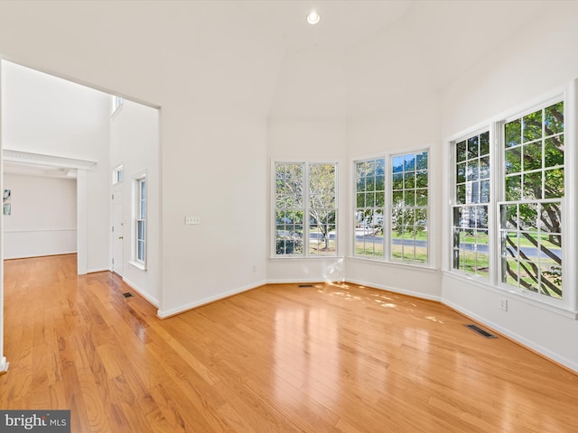 unfurnished room with visible vents, wood finished floors, recessed lighting, a high ceiling, and baseboards