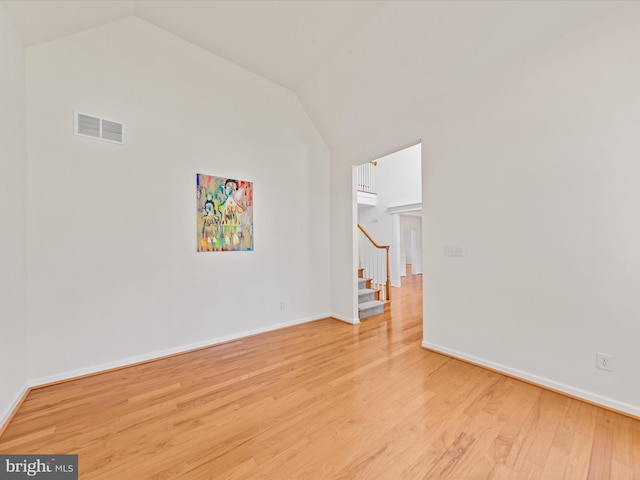 unfurnished room with stairs, vaulted ceiling, visible vents, and light wood finished floors