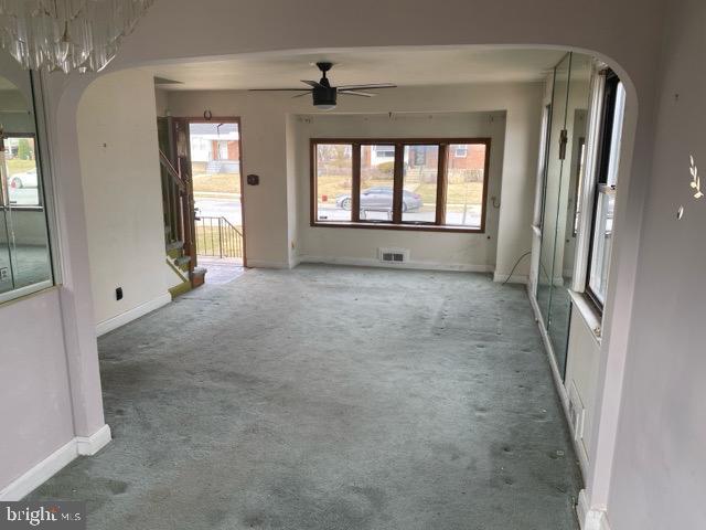 unfurnished living room with visible vents, arched walkways, carpet, and plenty of natural light