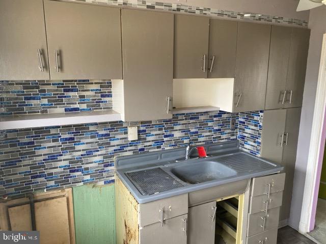 kitchen featuring decorative backsplash, light countertops, and a sink