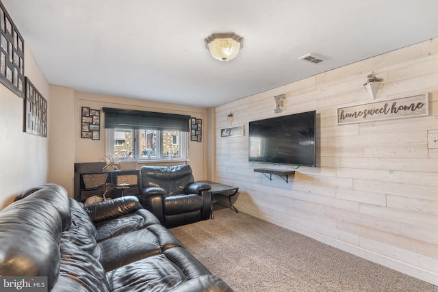 living area featuring visible vents, carpet floors, and wood walls