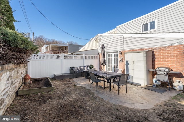 view of patio with french doors, a grill, a vegetable garden, and fence