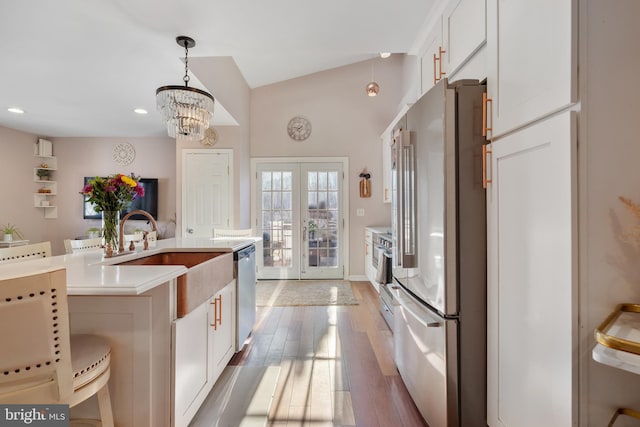 kitchen featuring wood finished floors, freestanding refrigerator, a sink, light countertops, and dishwasher