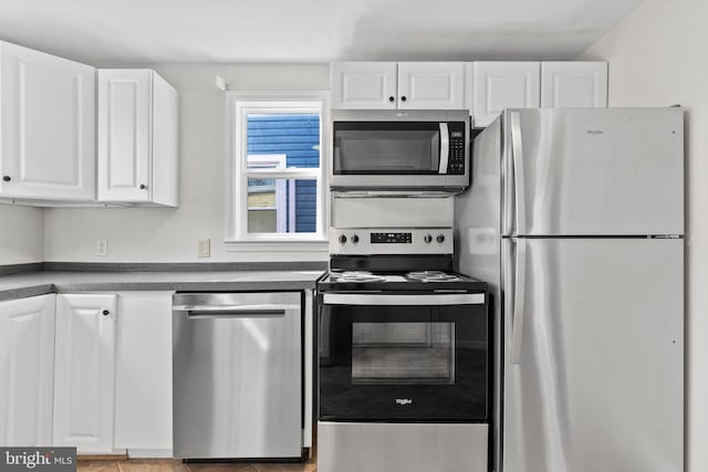 kitchen featuring dark countertops, white cabinets, and appliances with stainless steel finishes