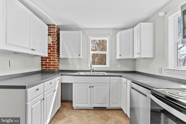 kitchen featuring a sink, stainless steel dishwasher, dark countertops, and white cabinets