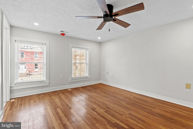 unfurnished room with visible vents, a textured ceiling, baseboards, and wood-type flooring