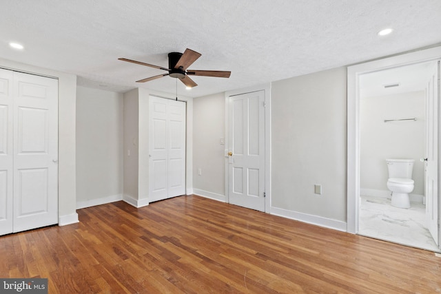 unfurnished bedroom with wood finished floors, multiple closets, and a textured ceiling