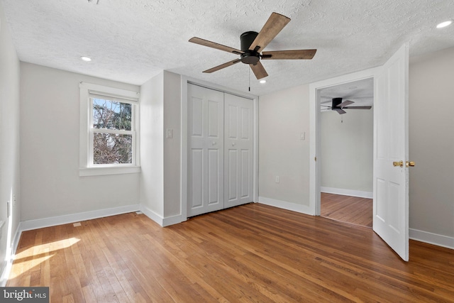 unfurnished bedroom featuring ceiling fan, baseboards, a textured ceiling, and hardwood / wood-style floors