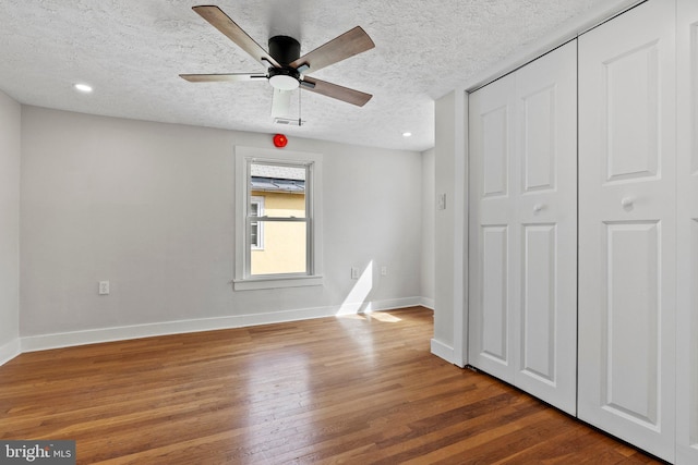 unfurnished bedroom with wood finished floors, baseboards, recessed lighting, a closet, and a textured ceiling