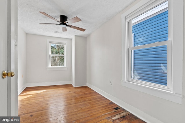 empty room featuring visible vents, a ceiling fan, a textured ceiling, wood-type flooring, and baseboards