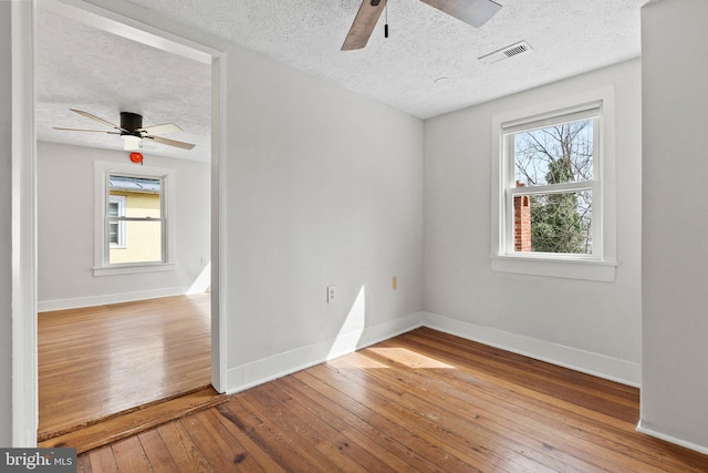 spare room with a ceiling fan, baseboards, visible vents, and wood-type flooring