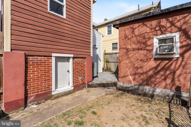 exterior space featuring cooling unit, brick siding, and fence