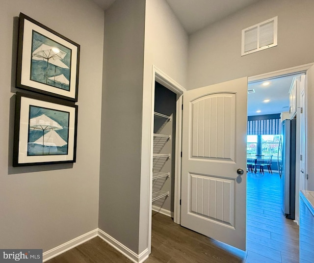 corridor featuring visible vents, baseboards, and wood finished floors