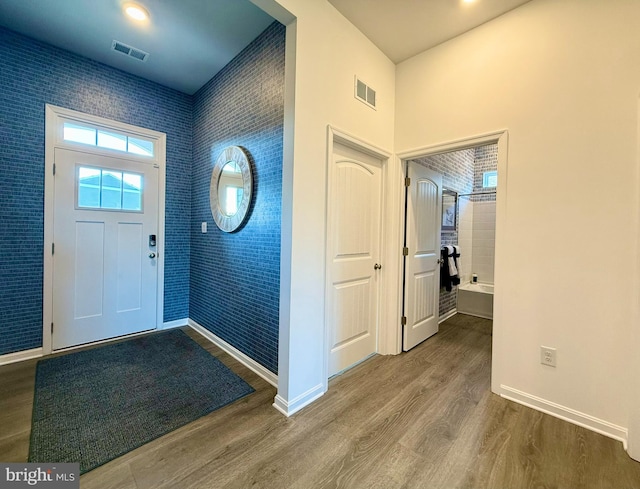 foyer entrance with visible vents, baseboards, and wood finished floors