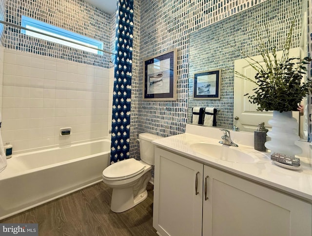 full bath featuring vanity, wood finished floors, shower / bath combo, tile walls, and toilet