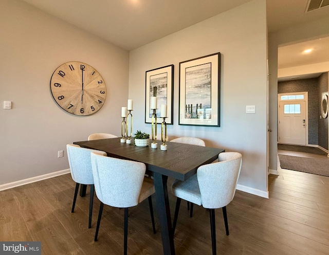 dining area with dark wood-type flooring, baseboards, and visible vents