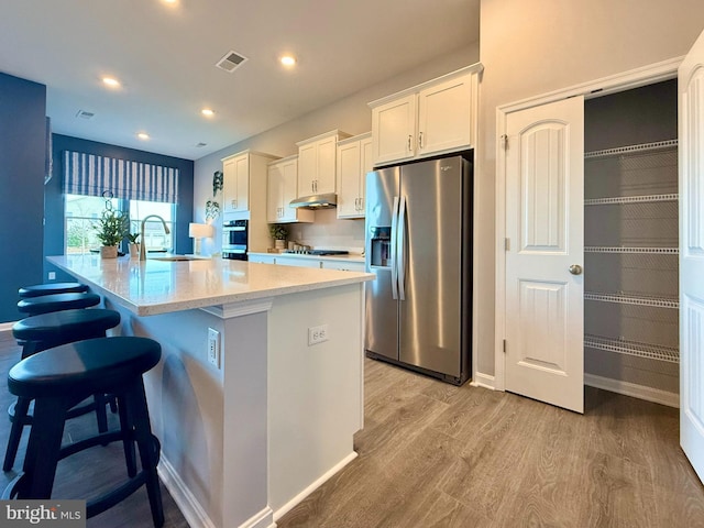 kitchen featuring visible vents, a sink, a spacious island, appliances with stainless steel finishes, and white cabinets