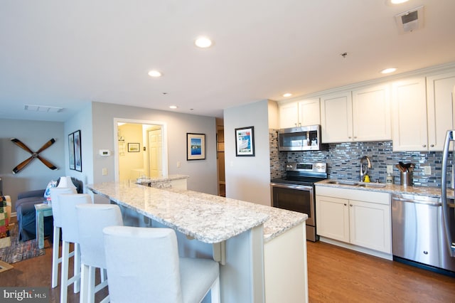 kitchen with a sink, stainless steel appliances, visible vents, and wood finished floors