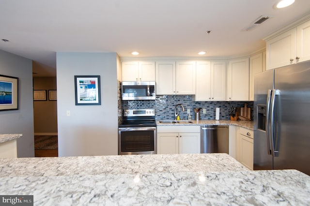 kitchen featuring visible vents, a sink, backsplash, white cabinetry, and stainless steel appliances