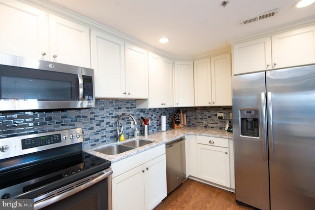 kitchen featuring wood finished floors, visible vents, a sink, stainless steel appliances, and backsplash