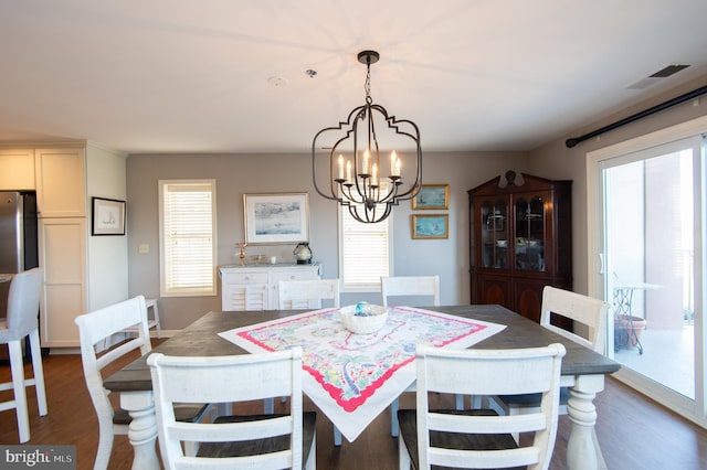 dining area with a wealth of natural light, dark wood-type flooring, and an inviting chandelier