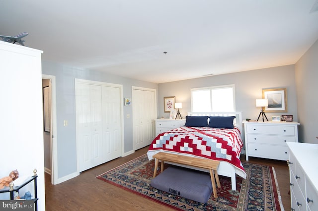 bedroom featuring baseboards, multiple closets, and dark wood-style flooring