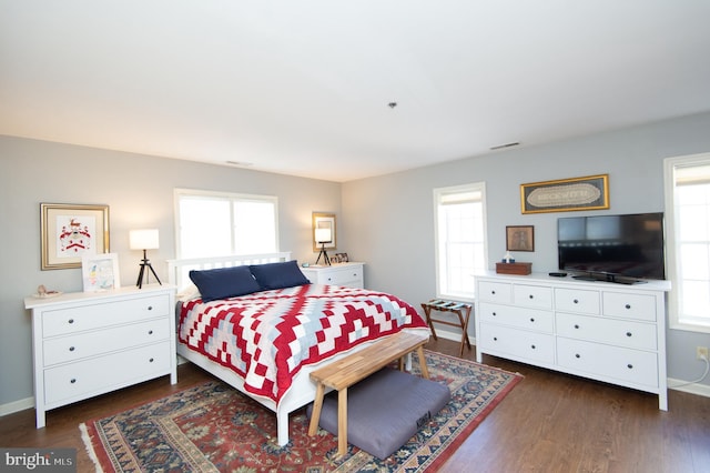 bedroom with visible vents, baseboards, and dark wood finished floors