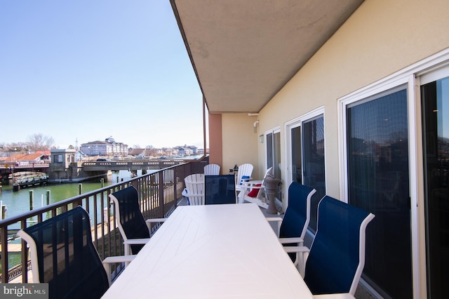 balcony featuring outdoor dining area and a water view