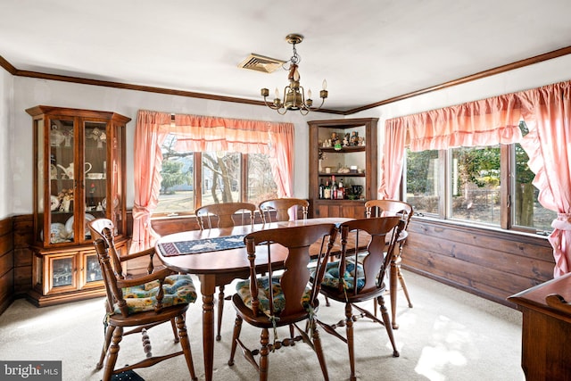 dining room featuring wooden walls, visible vents, crown molding, light colored carpet, and a chandelier