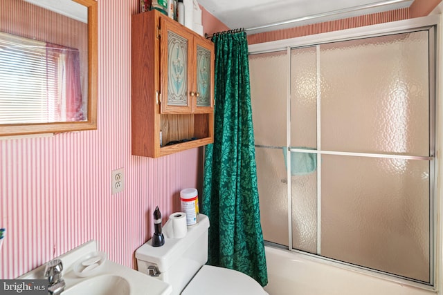 bathroom featuring combined bath / shower with glass door, toilet, vanity, and wallpapered walls