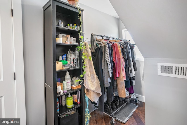 spacious closet with vaulted ceiling, visible vents, and wood finished floors