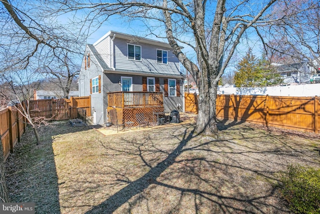 rear view of property featuring stucco siding, a deck, and a fenced backyard