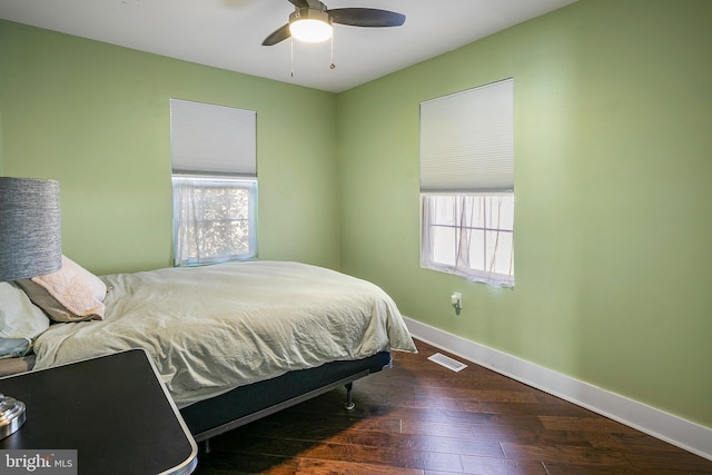 bedroom featuring a ceiling fan, wood finished floors, visible vents, and baseboards