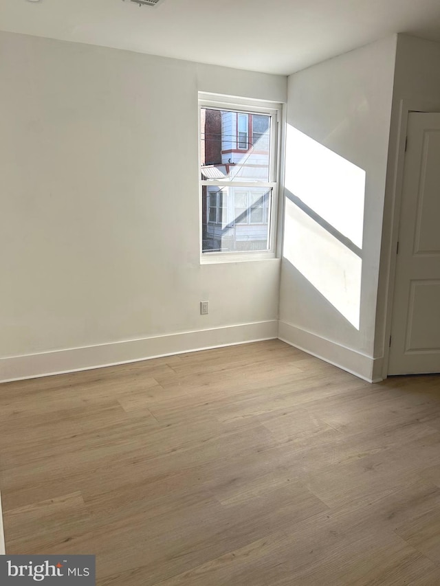 spare room featuring light wood-type flooring, baseboards, and visible vents