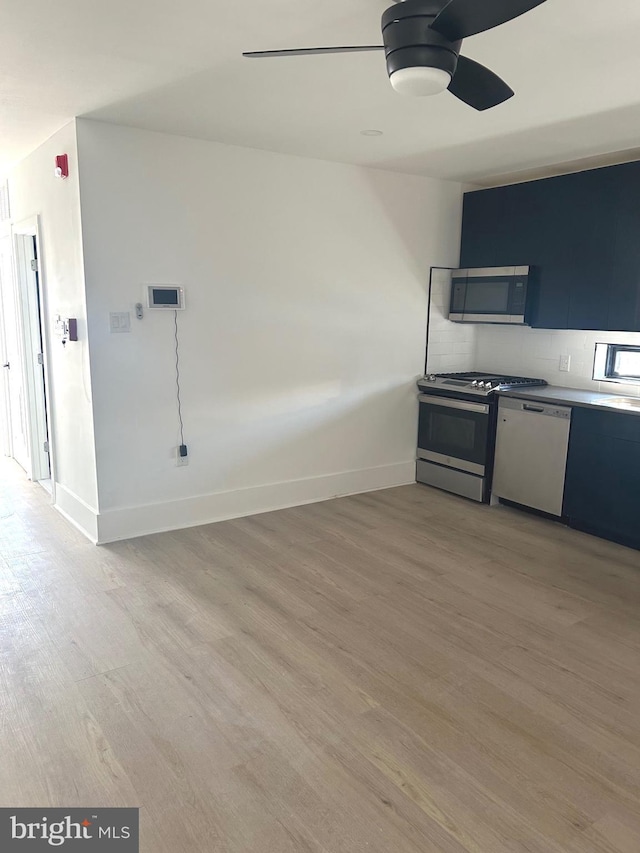 kitchen featuring stainless steel appliances, baseboards, a ceiling fan, and light wood finished floors