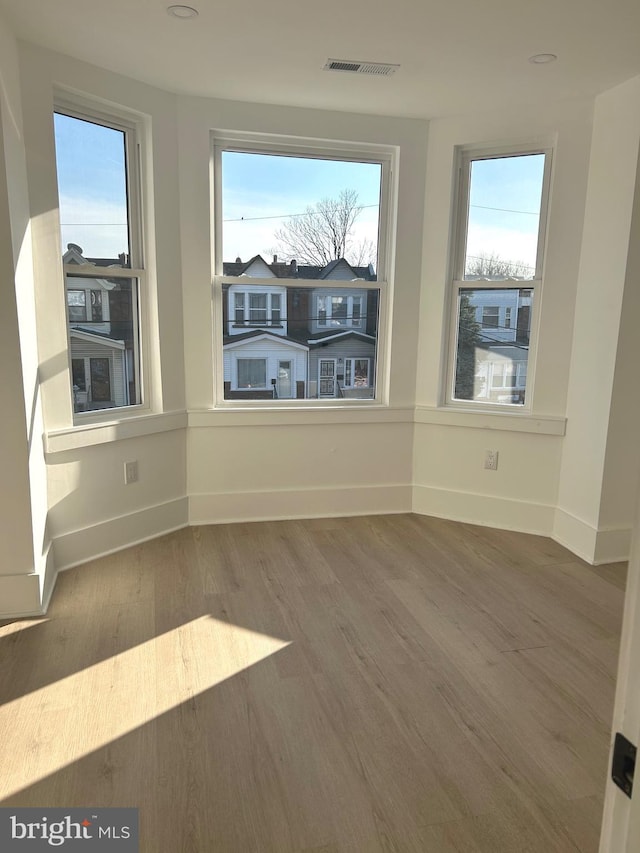 spare room with visible vents, baseboards, and wood finished floors