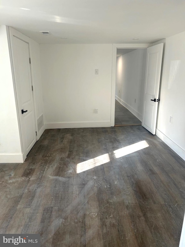 unfurnished room featuring visible vents, baseboards, and dark wood-style flooring