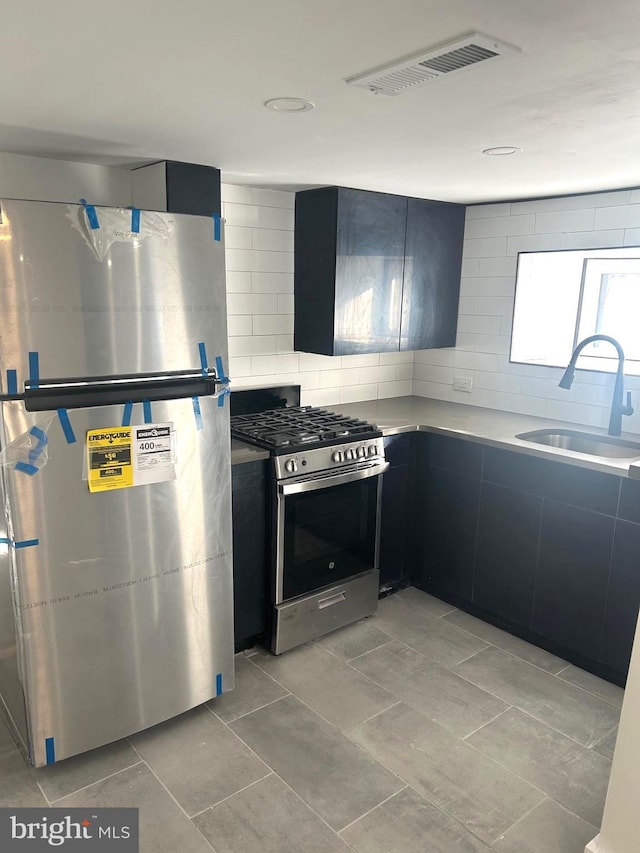 kitchen featuring visible vents, light countertops, appliances with stainless steel finishes, dark cabinetry, and a sink