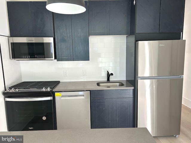 kitchen with light wood-type flooring, modern cabinets, a sink, tasteful backsplash, and stainless steel appliances