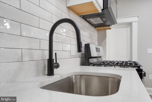 kitchen with light stone counters, a sink, and exhaust hood