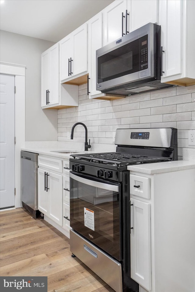 kitchen with stainless steel appliances, white cabinets, light countertops, and light wood finished floors