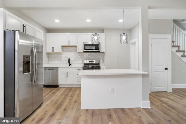 kitchen with stainless steel appliances, white cabinetry, backsplash, and light countertops