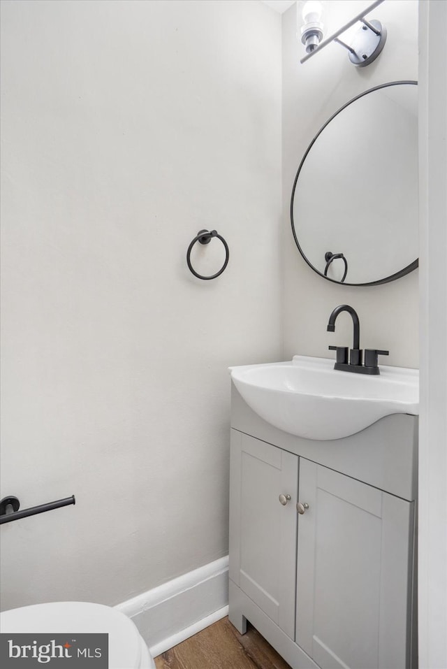 bathroom with toilet, vanity, baseboards, and wood finished floors