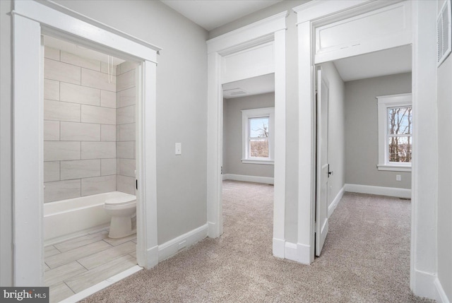 bathroom featuring a washtub, toilet, a shower, and baseboards