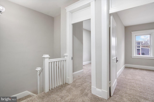 hall featuring baseboards, an upstairs landing, and carpet floors