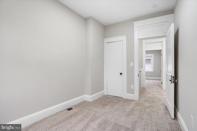 spare room with baseboards and light carpet