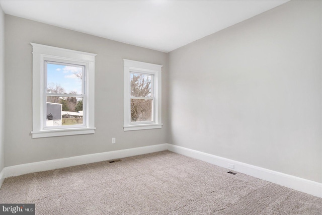 spare room featuring baseboards, visible vents, and carpet floors