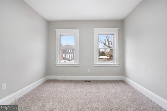 empty room featuring carpet flooring, baseboards, and a wealth of natural light