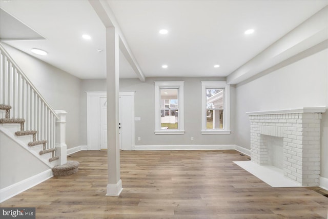 unfurnished living room with recessed lighting, light wood-style flooring, stairs, and baseboards