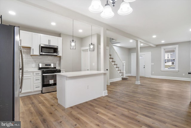 kitchen with tasteful backsplash, open floor plan, stainless steel appliances, white cabinets, and light wood finished floors